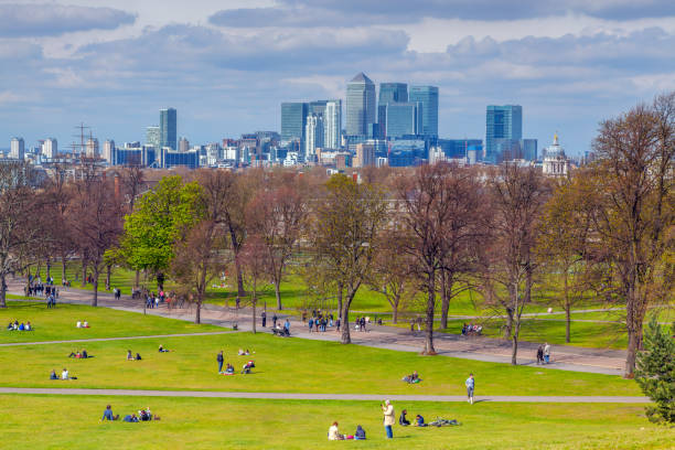 Greenwich park in London People relaxing in the Greenwich Park, in the background you can see the skyscrapers of Canary Wharf greenwich london stock pictures, royalty-free photos & images