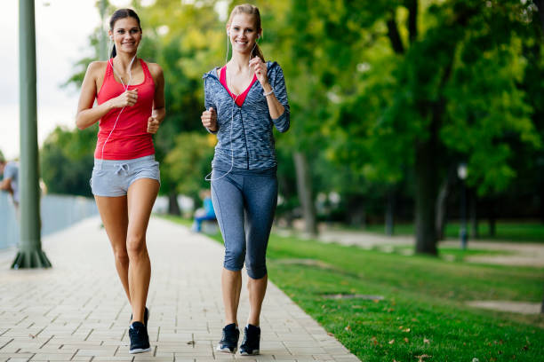 istock Two women jogging in park 860024420