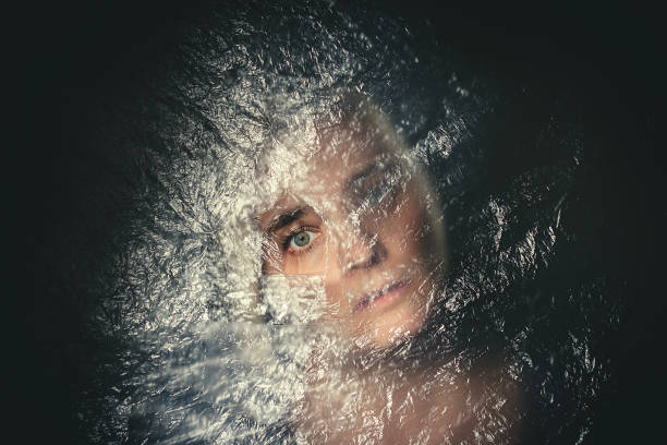 istock Woman with blank, terrified expression peeking through hole 860025456