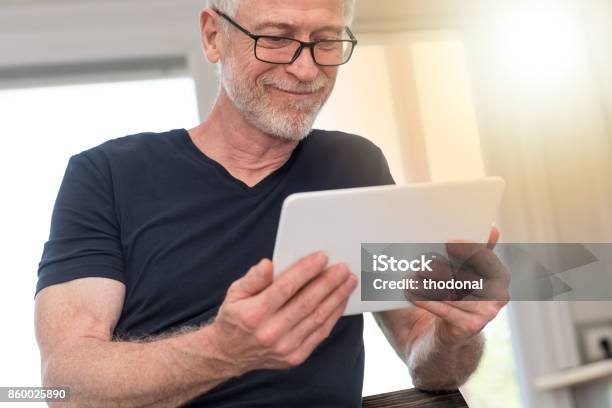 Reifer Mann Mit Digitaltablette Lichteffekt Stockfoto und mehr Bilder von 60-64 Jahre - 60-64 Jahre, Alter Erwachsener, Brille
