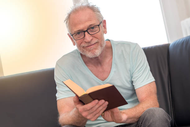 istock Portrait of mature man reading a book, light effect 860025930