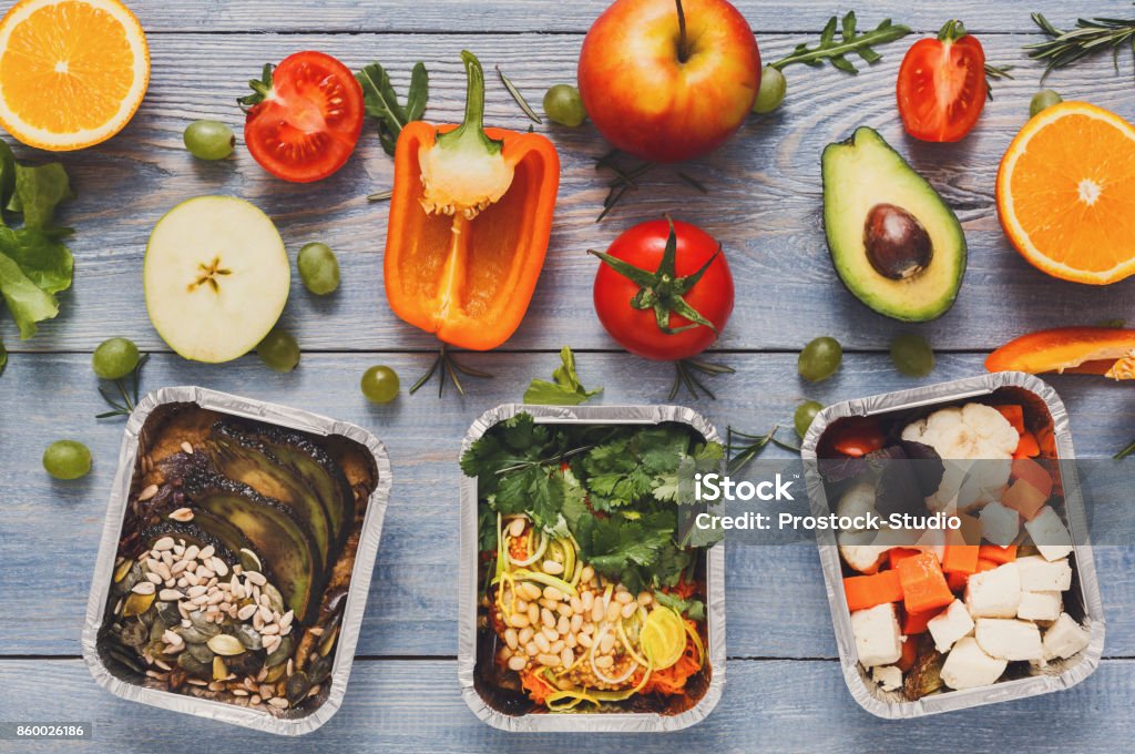 Healthy lunch in boxes with fresh vegetables on blue wood background Healthy food delivery, lunch in foil boxes with fresh vegetables on blue wood background. Meals take away and delivery concept. Meal Stock Photo