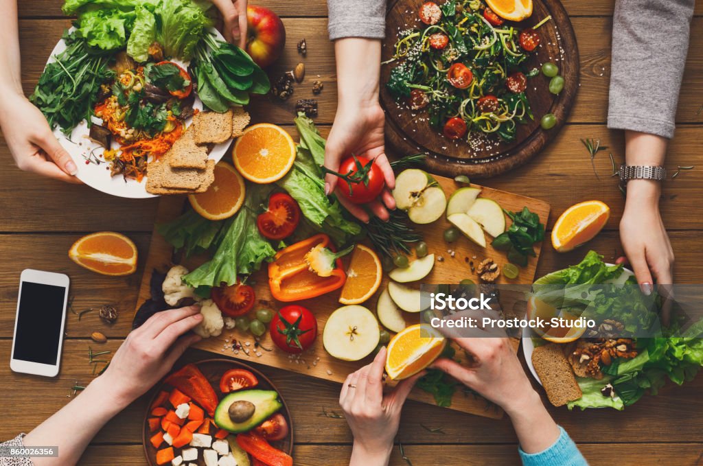 Dinner table, women eat healthy food at home kitchen Eating healthy food, fruits and vegetables dinner table. Women at home together, top view, flat lay, crop Cooking Class Stock Photo