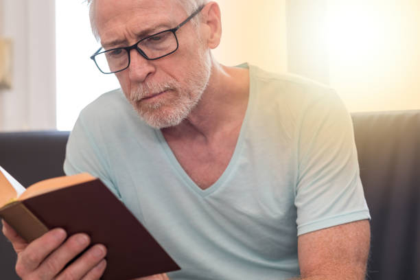 istock Portrait of mature man reading a book, light effect 860026498
