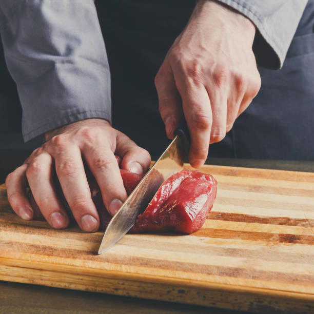 istock Chef cutting filet mignon on wooden board at restaurant kitchen 860031542
