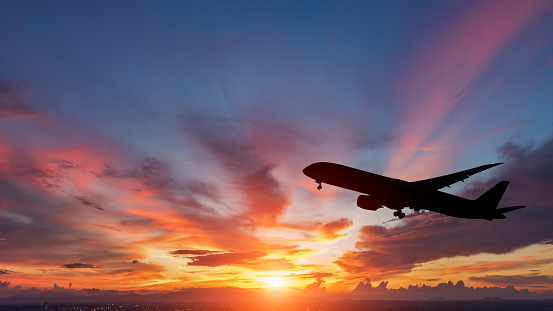 The silhouette of a passenger plane flying in sunset.