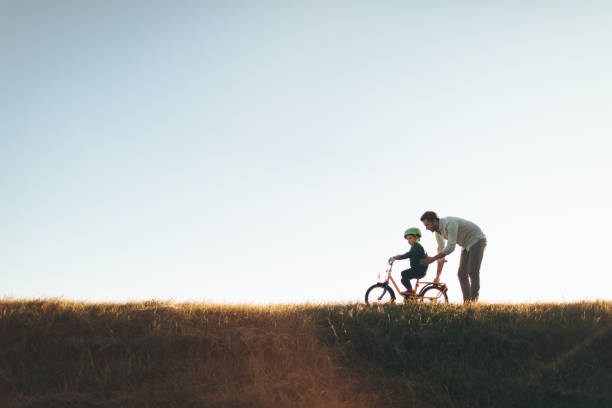 Father and son on a bicycle lane Photo of a young boy and his father on a bicycle lane, learning to ride a bike. bicycle cycling school child stock pictures, royalty-free photos & images