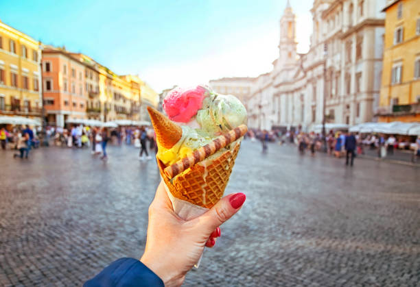 italienne cornet de crème glacée – qui s’est tenue dans la main sur le fond de la place navone - gelato photos et images de collection