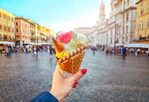 итальянский лед - сливочный конус, удерживаемый в руке на фоне площади навона - italian dessert фотографии стоковые фото и изображения