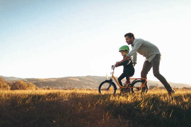 Father and son on a bicycle lane Photo of a young boy and his father on a bicycle lane, learning to ride a bike. outdoor living stock pictures, royalty-free photos & images
