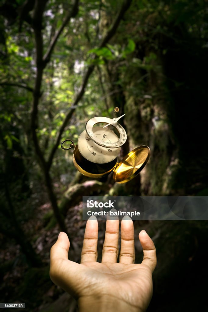 Surrealistic disintegrate compass floating over hand Surrealistic disintegrate Brass compass floating over hand in the middle of forest Brass Stock Photo