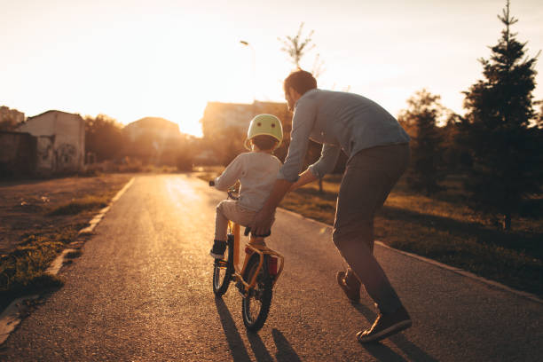 vater und sohn auf einem fahrradweg - sportschutzbekleidung stock-fotos und bilder