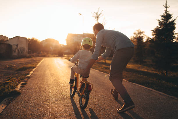 Father and son on a bicycle lane Photo of a young boy and his father on a bicycle lane, learning to ride a bike. bycicle stock pictures, royalty-free photos & images