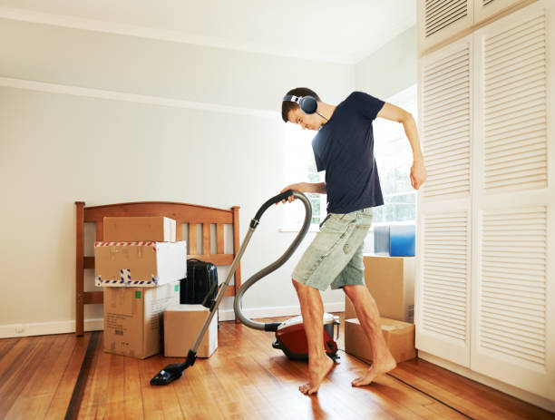 Moving in got him in such a mood! Shot of a young man vacuuming his new place before unpacking bachelor stock pictures, royalty-free photos & images