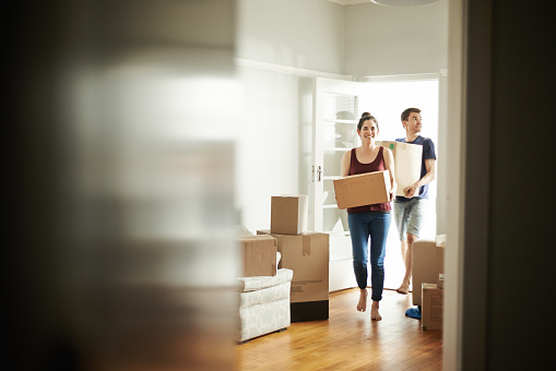 Shot of a young couple carrying boxes into their new place