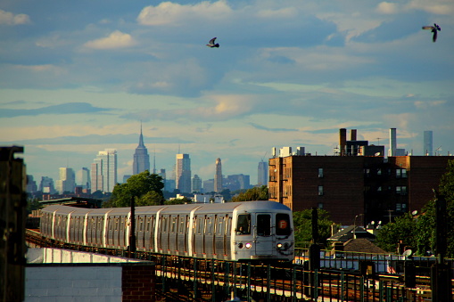 Elevated subway F line in southern Brooklyn in Brighton Beach and distant skyscrapers of Manhattan skyline in the background. Photo taken in summer afternoon.