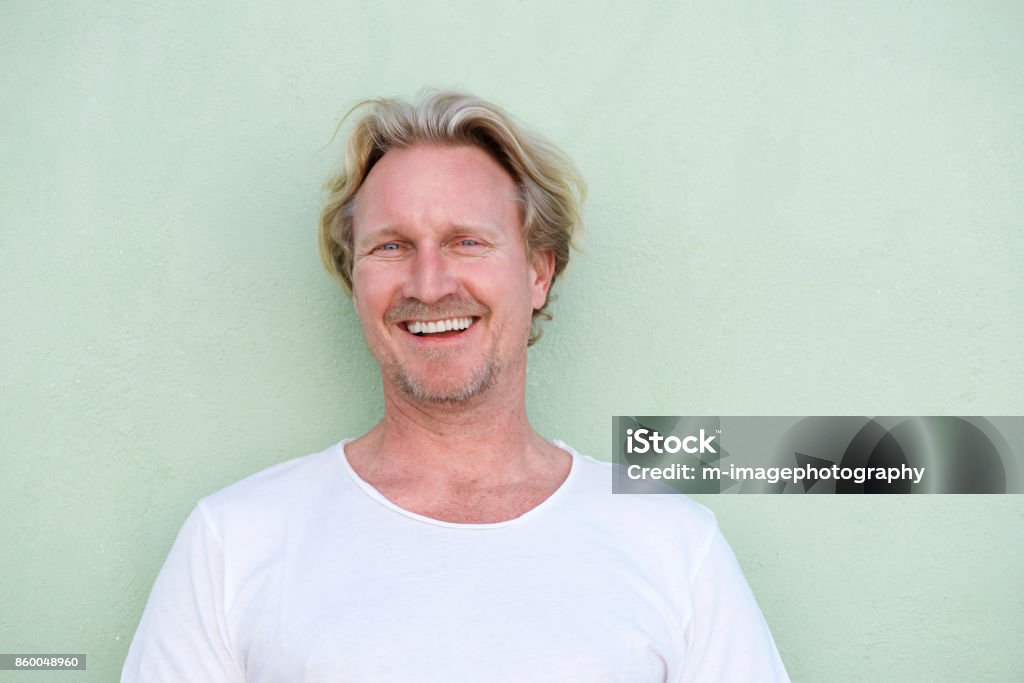 Усміхнений чоловік середнього віку, що стоїть на зеленому тлі - Роялті-фрі Зелений фон Стокове фото