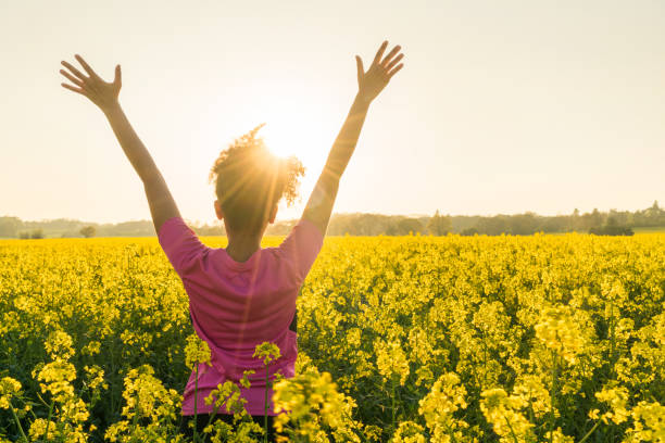 混血アフリカ系アメリカ人女の子若い女性アスリート ランナー ティーンエイ ジャー黄金の夕日や日の出の腕上げた黄色い花のフィールドで祝う - arms raised ストックフォトと画像