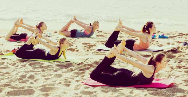 istock Young women training yoga positions on beach 860049736