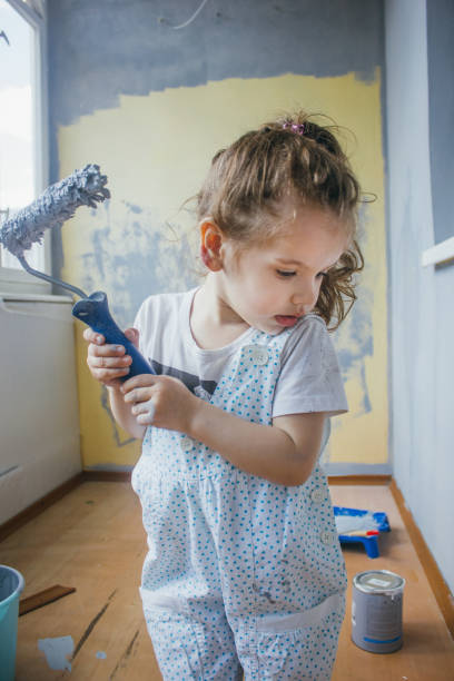 istock Little girl holding paint roller by hands at room. 860053512