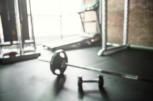 Blurred of GYM with barbell and dumbbell and treadmill in background