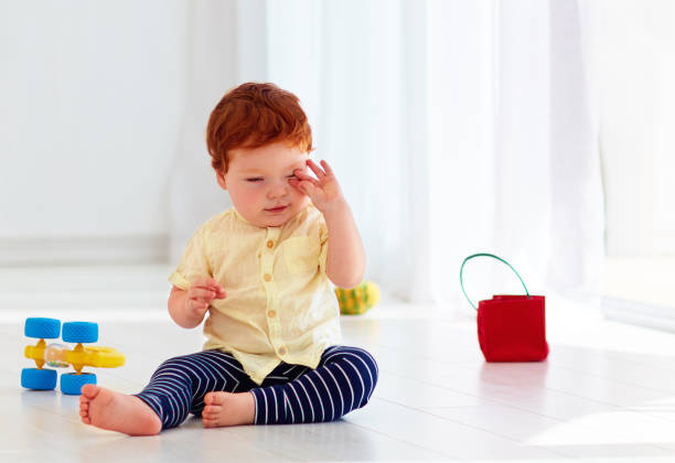 istock tired sleepy baby rubbing his eyes, ready for daytime sleep 860056430