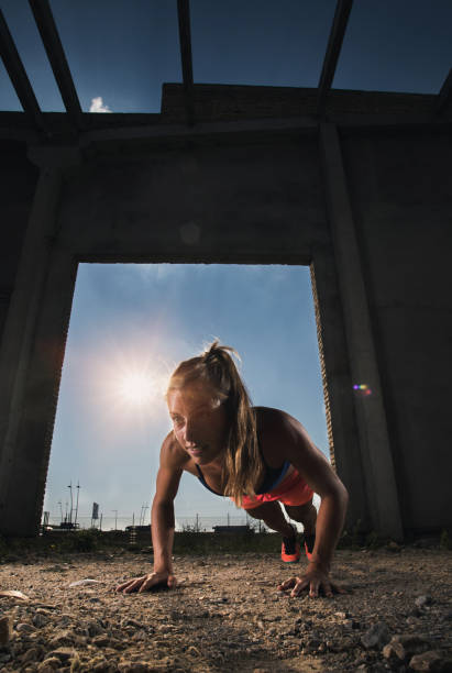 athlète féminine déterminée exerce des tractions sur les bras dans une vieille ruine. - athlete push ups muscular build female photos et images de collection