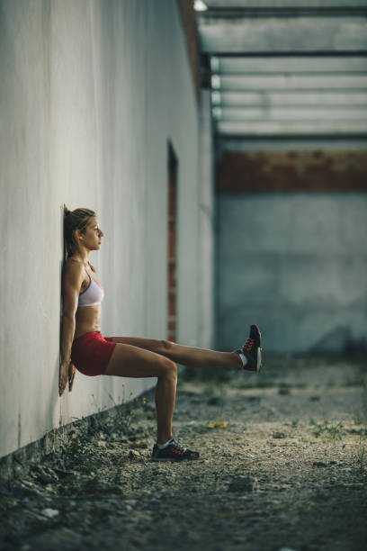 istock Athletic woman doing one-legged wall sit on a sports training. 860065478