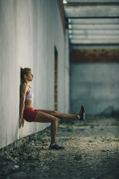 Athletic woman doing one-legged wall sit on a sports training ripl fitness