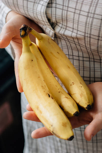 istock Woman holding three ripe bananas in arms 860066166