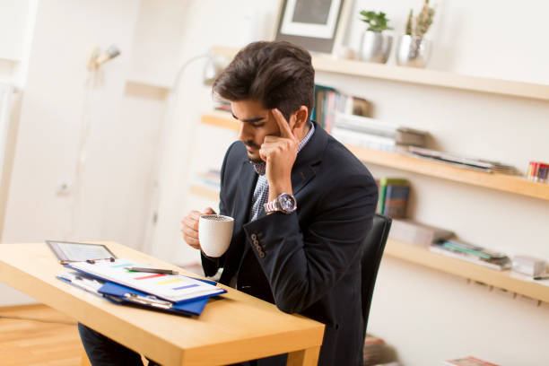 istock Businessman analyzing investment charts on digital tablet and drinking coffee at office 860072790
