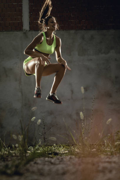 Happy female athlete making an effort while exercising high jumps.