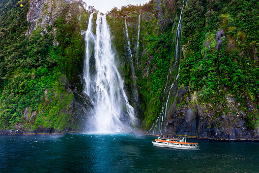 Stirling Falls at Milford Sound in South Island of New Zealand. Tourist ferry approaching Stirling Falls, the greatest waterfalls in Milford Sound, New Zealand.