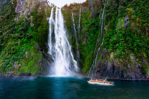 Stirling Falls at Milford Sound, New Zealand Stirling Falls at Milford Sound in South Island of New Zealand. Tourist ferry approaching Stirling Falls, the greatest waterfalls in Milford Sound, New Zealand. milford sound stock pictures, royalty-free photos & images