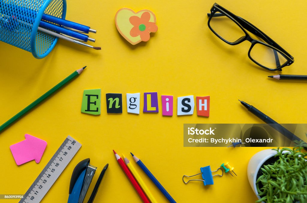 English word of carved letters on yellow background with office or school supplies,English language learning concept English word of carved letters on yellow background with office or school supplies,English language learning concept. English Language Stock Photo