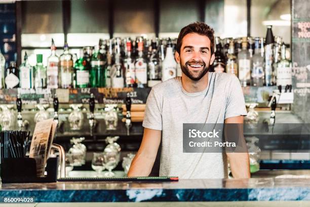 Portrait Of Bartender Standing At Bar Counter Stock Photo - Download Image Now - Bartender, T-Shirt, Bar - Drink Establishment