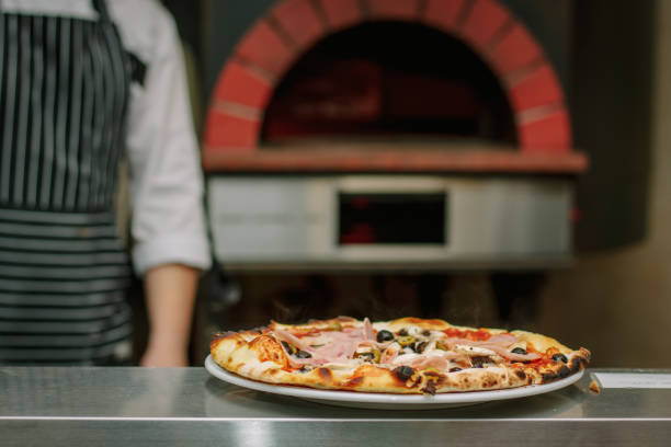 istock Fresh prepared pizza with the traditional pizza oven on background. 860099844