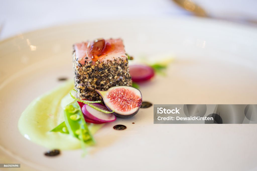 Gourmet pork dish covered in crushed black pepper with green figs on the side Close up of a gourmet pork dish covered in crushed black pepper with sweet green figs on the side Gourmet Stock Photo