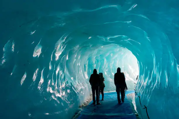 Silhouettes of people visiting thee ice cave of the Mer de Glace glacier,  in Chamonix Mont Blanc Massif, The Alps, France