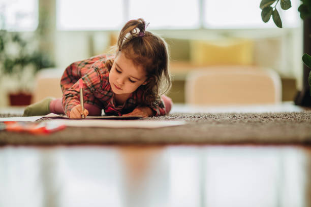 カーペット自宅でリラックスしながらフェルトペンで書いている小さな女の子。 - childs drawing child preschool crayon ストックフォトと画像