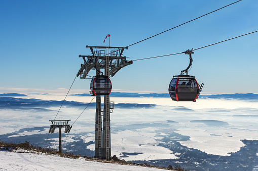 Gondola lift. Cabin of ski-lift in the ski resort in the early morning at dawn with mountain peak in the distance. Winter snowboard and skiing concept