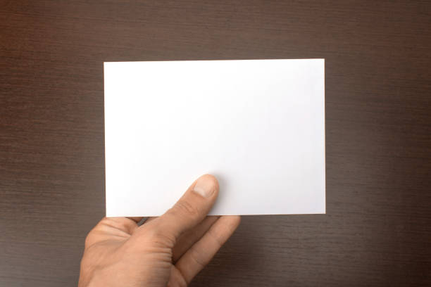 istock Blank postcard in hand on wooden background. Leaflet A6 mockup 860117004