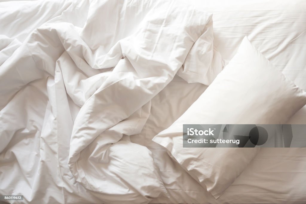 Messy bed. White pillow with blanket on bed unmade. Top view. Messy bed. White pillow with blanket on bed unmade. Concept of relaxing after morning. With lighting window. Top view. Bed - Furniture Stock Photo