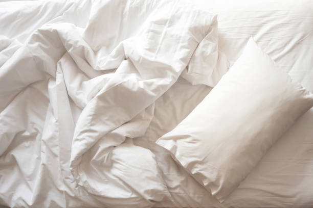 Messy bed. White pillow with blanket on bed unmade. Top view. Messy bed. White pillow with blanket on bed unmade. Concept of relaxing after morning. With lighting window. Top view. fluffy blanket stock pictures, royalty-free photos & images