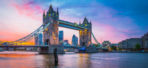 London Tower Bridge River Thames City skyscrapers illuminated sunset panorama Dramatic sunset skies above the iconic span of Tower Bridge framing the futuristic skyscrapers of the Square Mile financial district above the slow moving waters of the River Thames in the heart of London, Britain's vibrant capital city. historical geopolitical location photos stock pictures, royalty-free photos & images