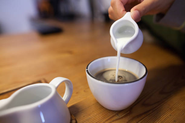 Woman hand pouring milk in coffee