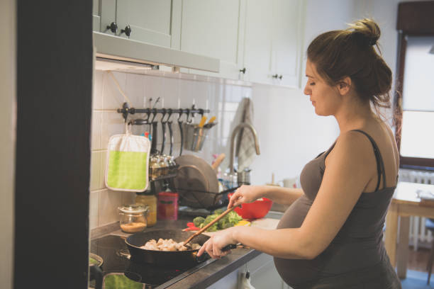 Hungry eight month pregnant woman preparing dinner