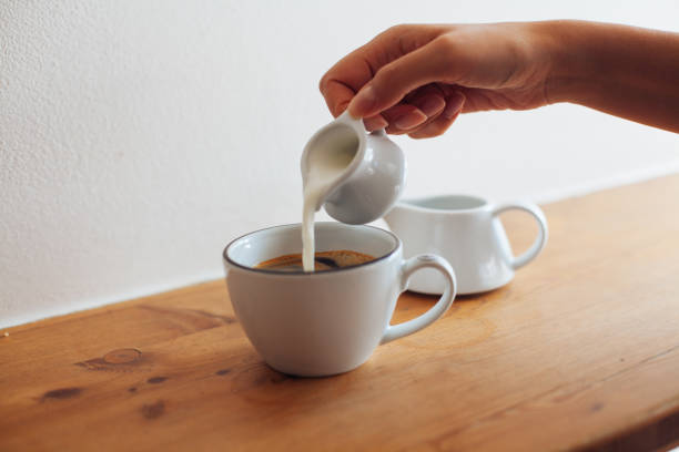 istock Woman hand pouring milk in coffee 860122106