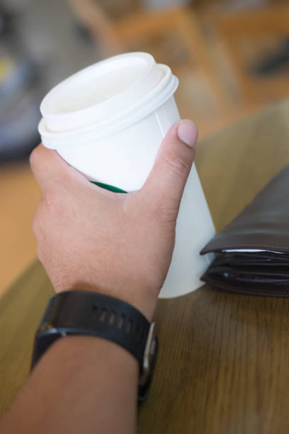 istock Male hand holding a coffee paper cup on wood table 860125896