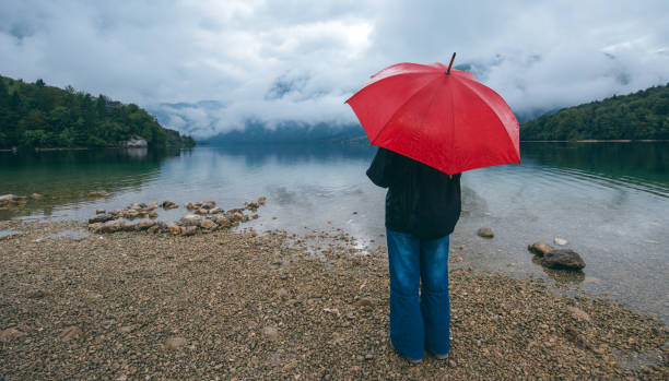 istock Woman with red umbrella contemplates on rain 860133594